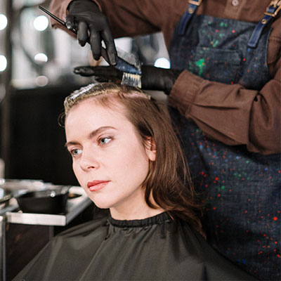 Woman receiving professional hair color treatment at home by IZA Beauty beautician.