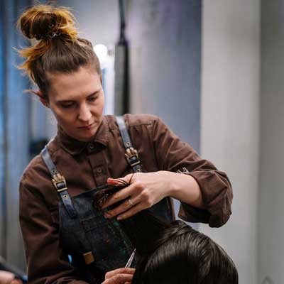 Professional hairstylist from IZA Beauty giving a stylish haircut to a female client at home